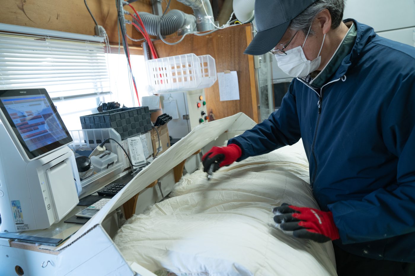 羽毛布団をほどき、羽毛を取り出す工程